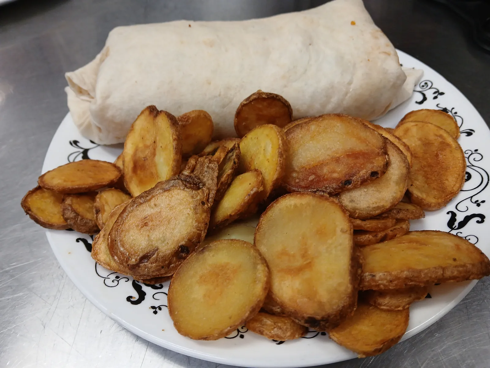 A breakfast burrito with a side of deep-fried sliced potatoes